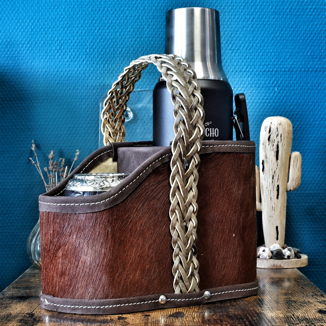 Matera premium en poil de vache chocolat garnie d'un Thermo Gaucho et d'un maté, démontrant sa capacité de transport idéale.