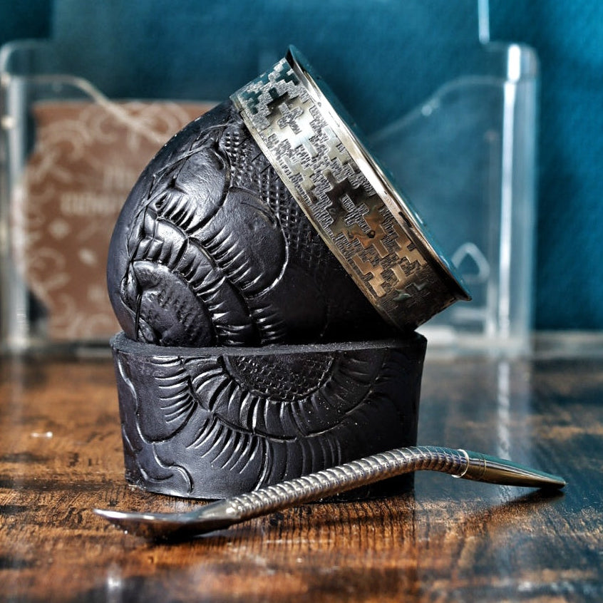 Vue latérale du maté montrant le cuir noir sculpté de motifs pétales et sa base large en anneau de cuir labrado pour une stabilité parfaite.