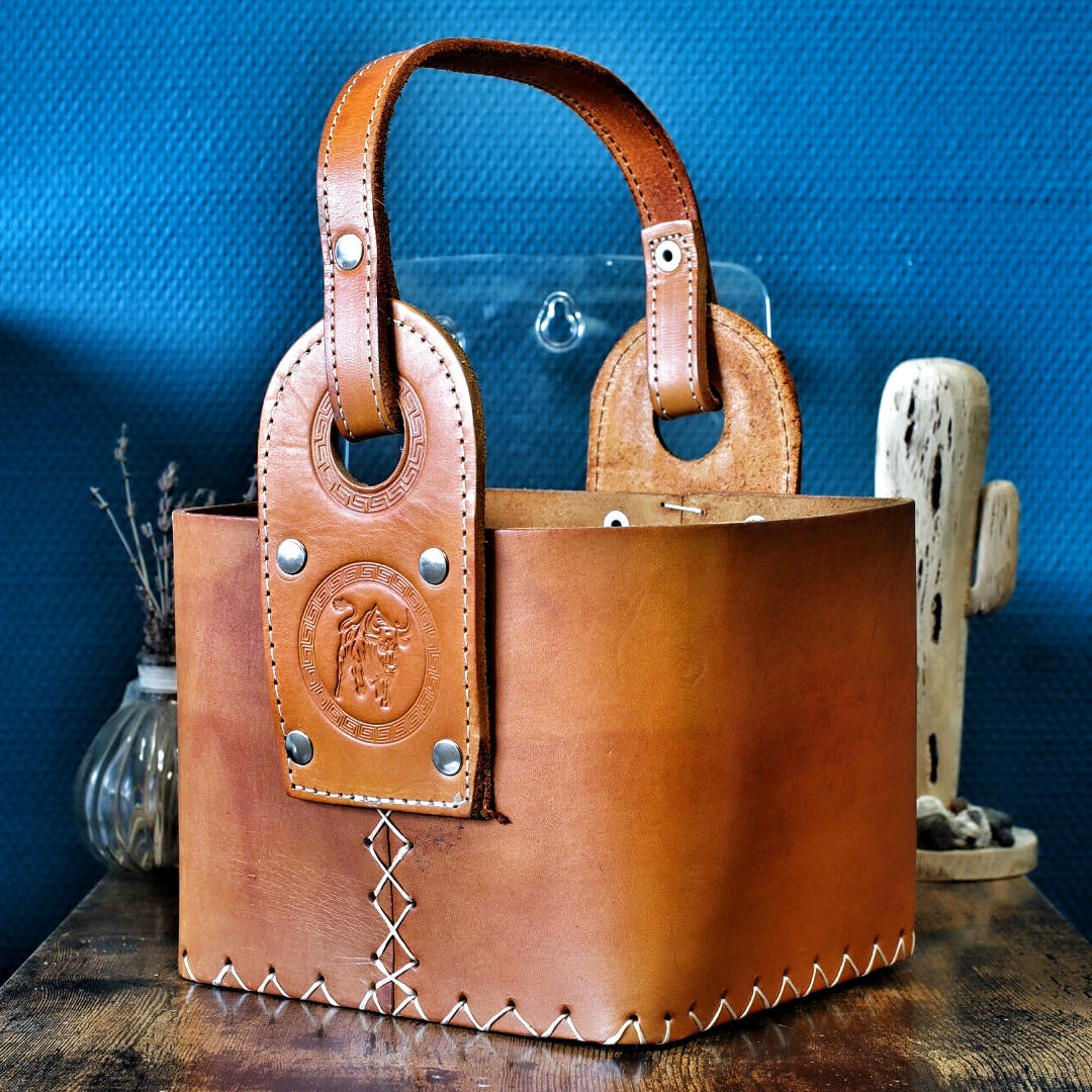 Matera artisanale en cuir camel, coutures blanches croisées et logo taureau en relief.