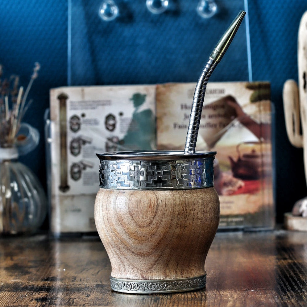 Maté Impérial barril en bois massif de caroubier avec sa bague centrale en bronze ciselé au motif traditionnel Pampa, sa virole lisse en alpaga et son anneau de base orné, livré avec une bombilla inox.