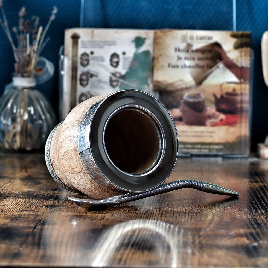: Vue détaillée des gravures géométriques et des motifs traditionnels complexes de style "Guarda Pampa" ciselés à la main sur la bague centrale en bronze du maté Impérial barril en algarrobo.