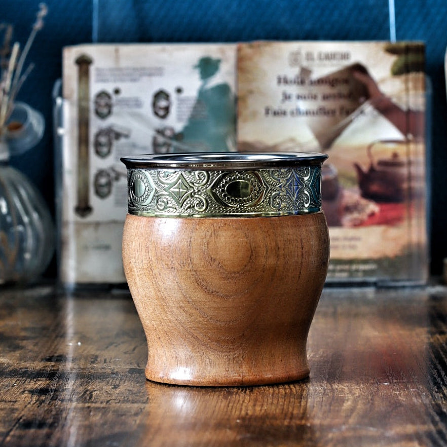 Maté argentin Impérial tonneau en bois d'algarrobo poli avec une virole brillante et lisse en alpaga, mis en valeur par un "fleje" central finement sculpté de motifs abstraits et de courbes, illustrant le savoir-faire des artisans orfèvres.