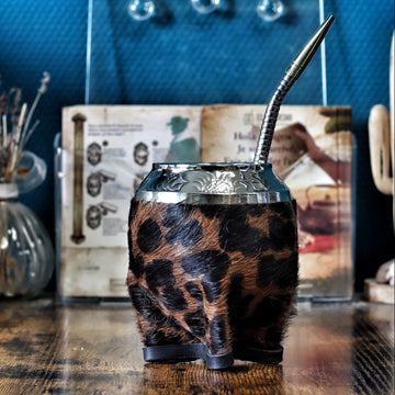 Maté de forme Torpedo artisanal en calebasse naturelle avec un double revêtement en cuir et motif Animal Print, surmonté d'une virole finement ciselée, présenté avec sa bombilla.