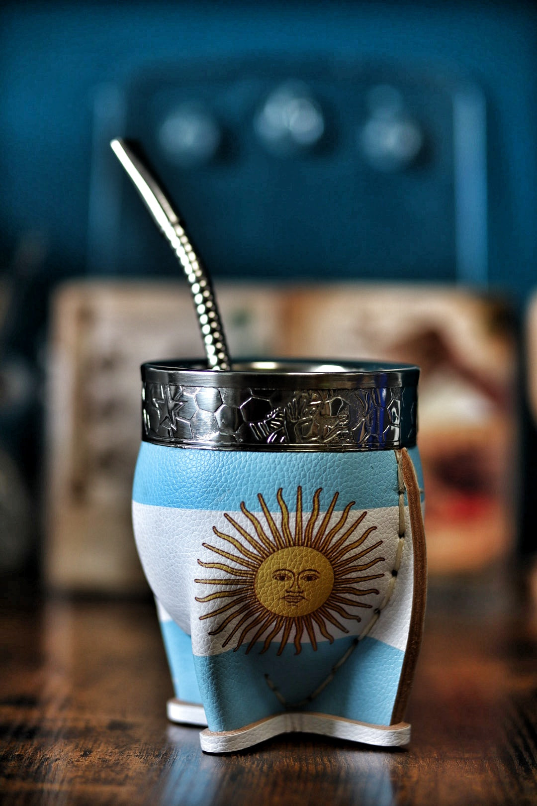 Maté argentin traditionnel en cuir ciel et blanc, mettant en valeur le Soleil de Mai et les coutures artisanales apparentes.