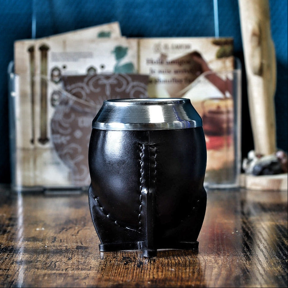 Maté Torpedo classique uruguayen en cuir lisse noir avec virole en acier inoxydable, posé verticalement sur table en bois.