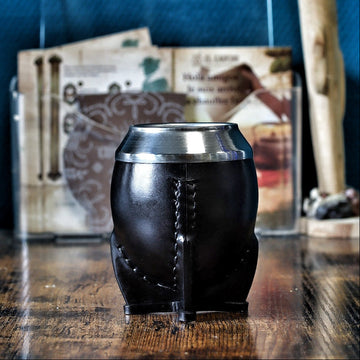 Maté Torpedo classique uruguayen en cuir lisse noir avec virole en acier inoxydable, posé verticalement sur table en bois.