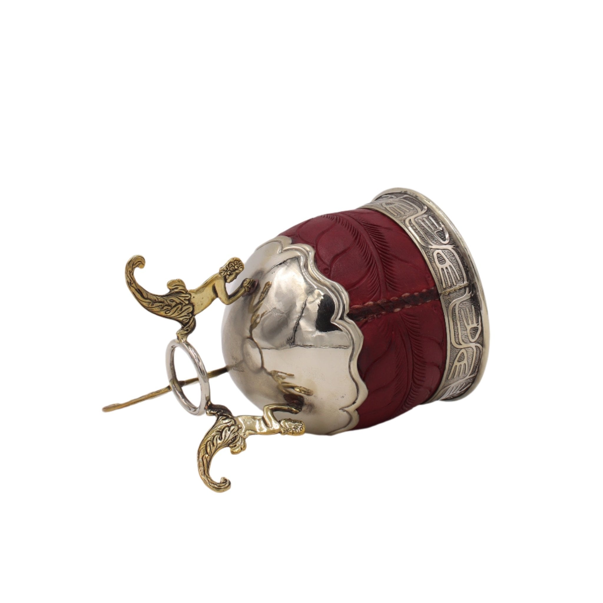 Profil : trépied bronze et reliefs du cuir rouge.