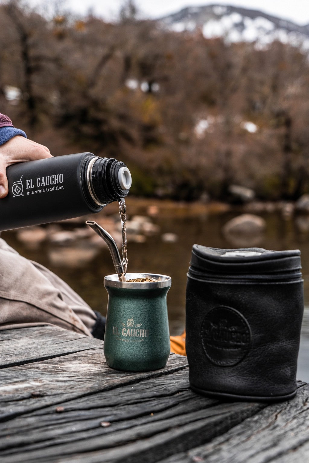 Le Mate Listo El Gaucho en mode thermos verse l'eau chaude dans un maté El Gaucho vert, au bord d'une rivière