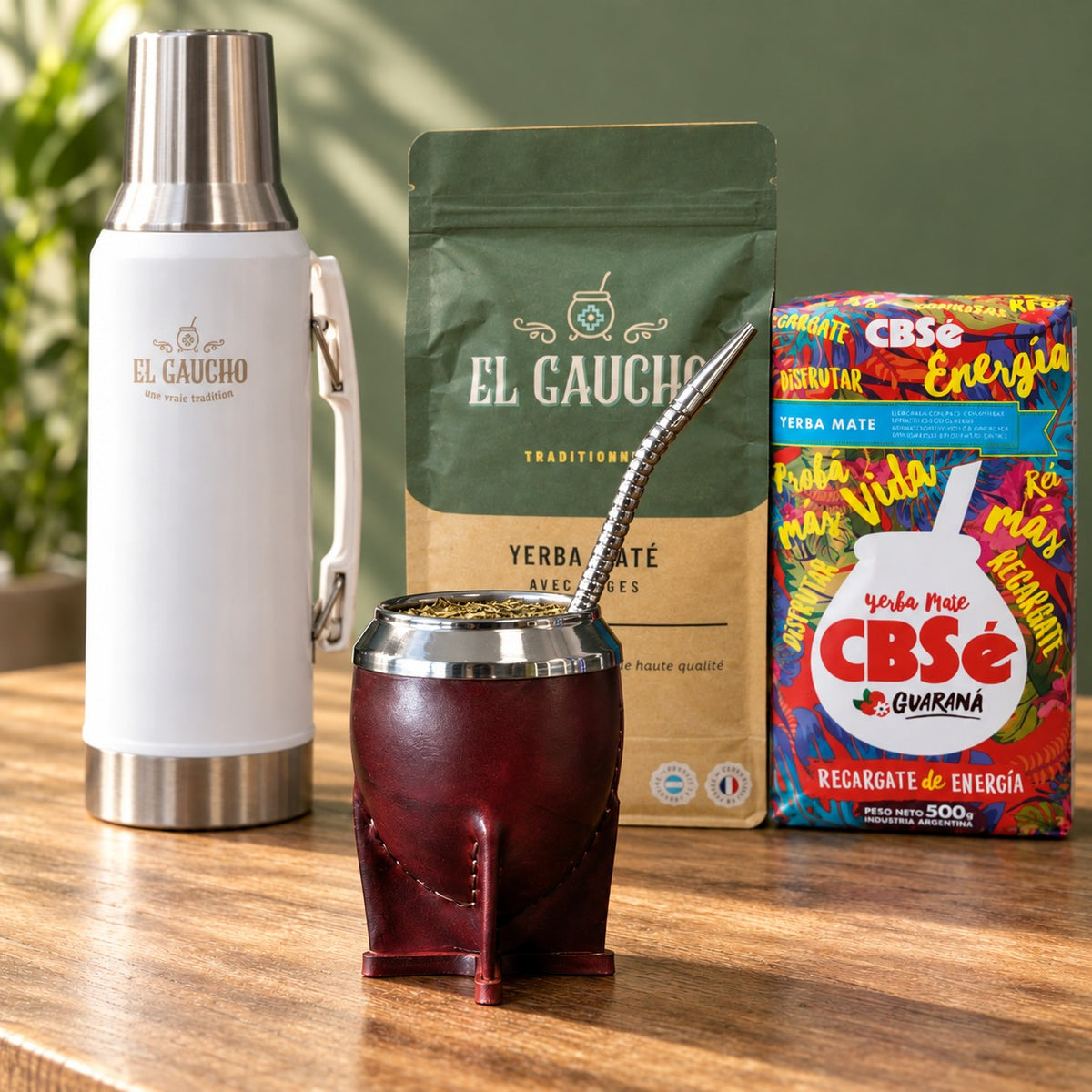 Pack Gaucho Classique Premium Thermo : maté Torpedo Deluxe cuir bordeaux, thermos blanc 1,2 L et deux paquets de yerba sur une table en bois