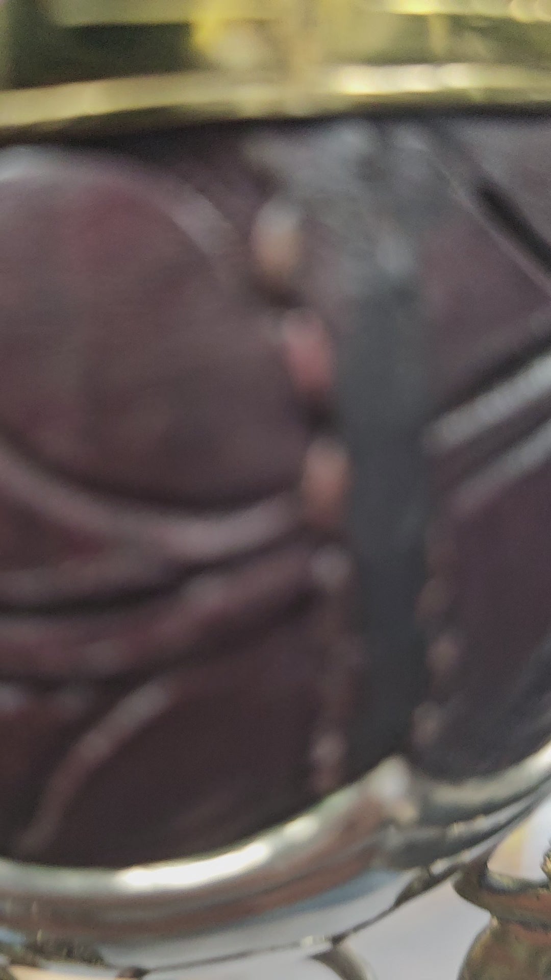 (Vidéo) Zoom main : détails de cuir brun et ciselure dorée.